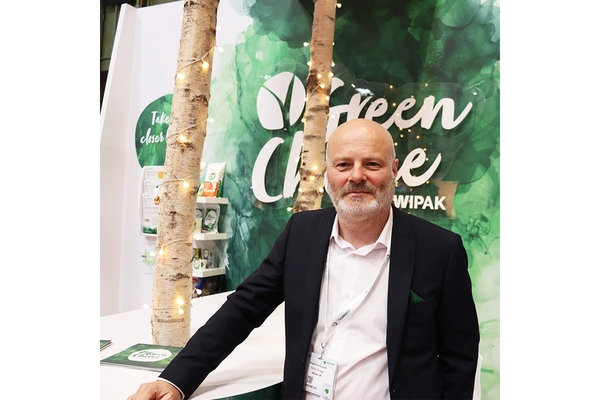 Man in suit at Wipak “Green Choice” packaging booth with birch decor